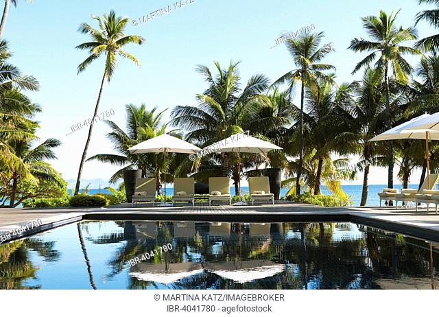 Sun loungers and parasols by a pool under palm trees, Vomo Island, Mamanuca Islands, Fiji