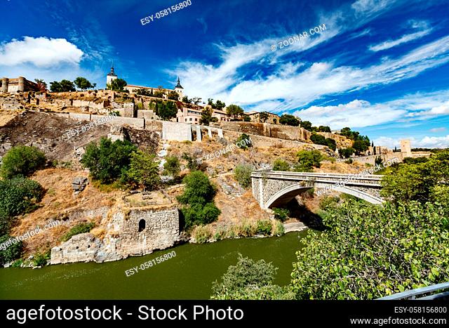 Panoramic view of Toledo Spain on a sunny summer day. Ancient stone walls and houses, blue sky and red-hot earth