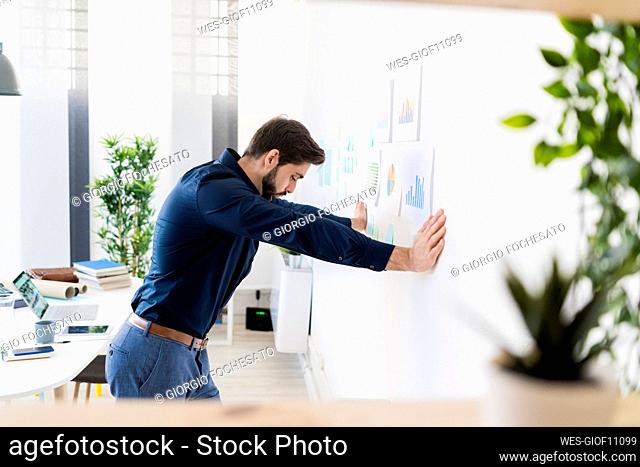 Exhausted male entrepreneur leaning on wall in office