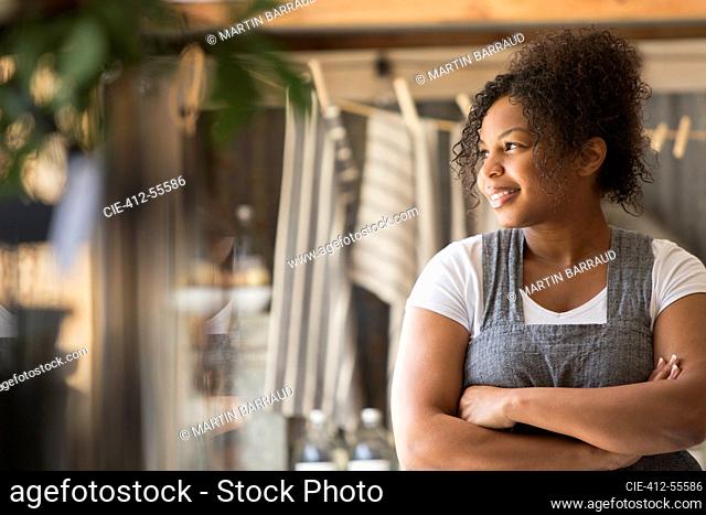 Smiling female shop owner looking away with arms crossed