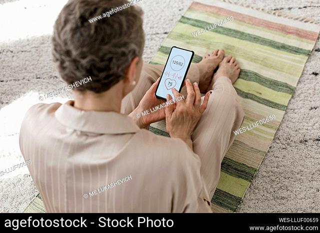 Mature woman checking data on smartphone at home
