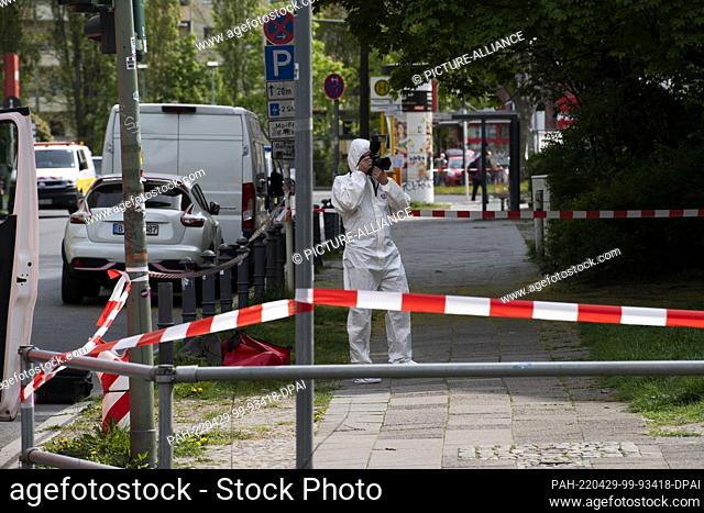 29 April 2022, Berlin: A member of the forensics team documents the situation at the scene in Maximilianstrasse, where a woman was killed in the open street