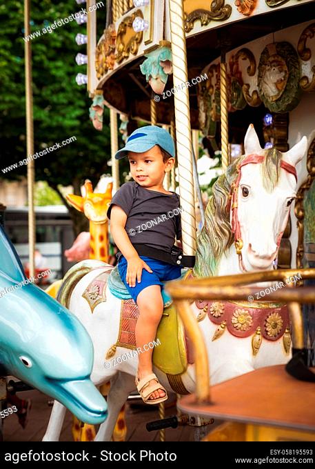 Little boy rides a traditional carousel white horse