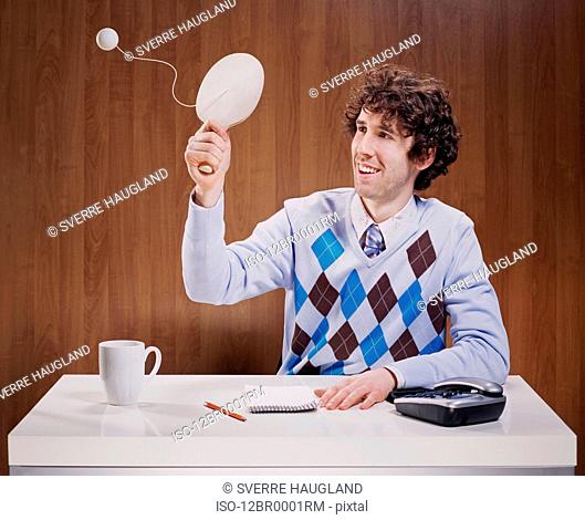 Businessman playing with paddle ball