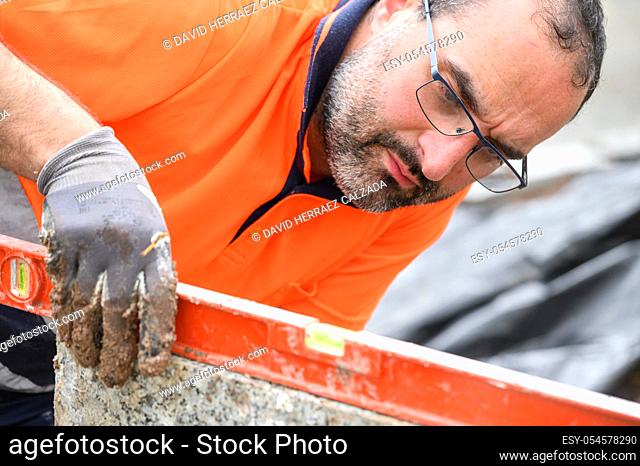 Construction worker checking the bubble level while working at construction site. Building construction