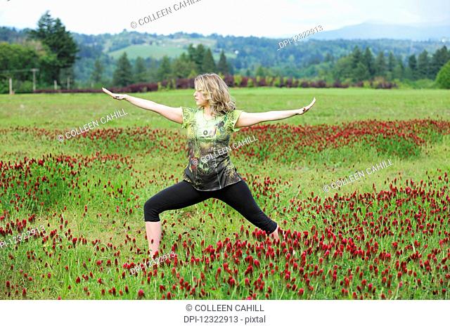 A woman does yoga in a field of wildflowers with mountains in the background; Oregon, United States of America