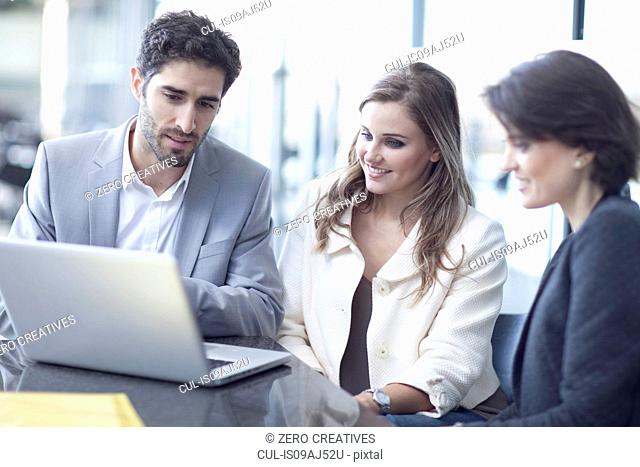 Three business colleagues with laptop in conference centre