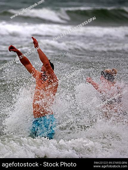 21 December 2023, Mecklenburg-Western Pomerania, Warnemünde: Hardened winter bathers take a dip in the storm-lashed water on the Baltic Sea beach