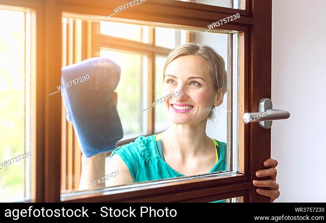 Beautiful woman cleaning the windows with cloth in spring
