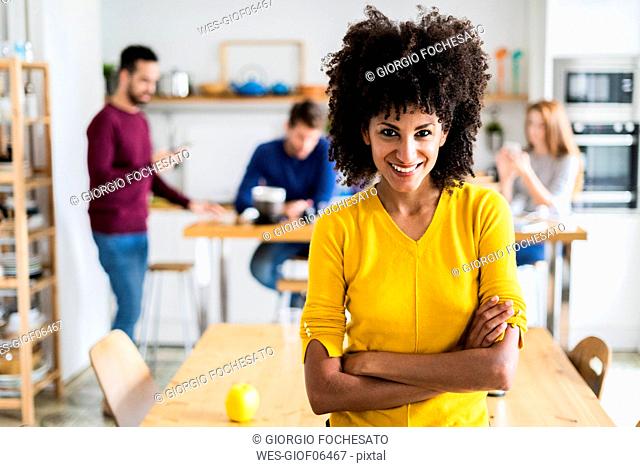 Portrait of smiling woman at dining table at home with friends in background