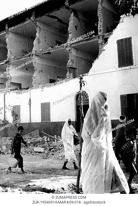 Sept. 14, 1954 - Orleansville, ALGERIA - Children and veiled women pass before the wreckage of an apartment house in search for food and water