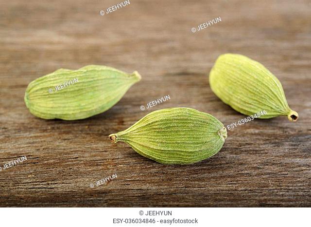 green cardamom pods on wooden background