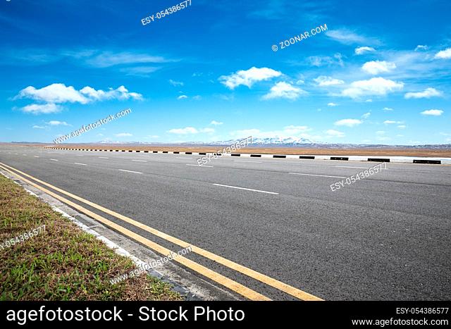 emtpy asphalt road and snow mountains in blue cloud sky