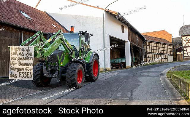 16 December 2023, Bavaria, Wüstenwelsberg: A tractor with a protest sign stands on a road and partially slows down traffic