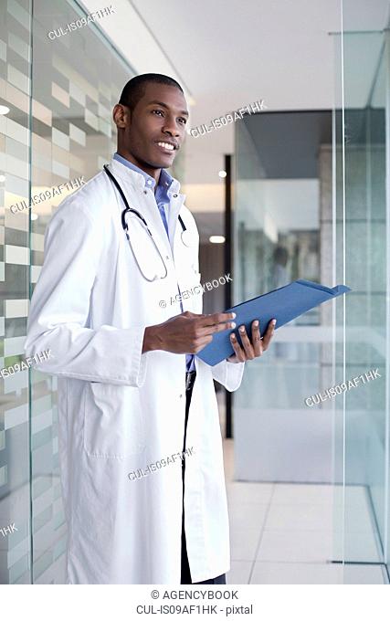 Doctor standing in hospital corridor holding paperwork