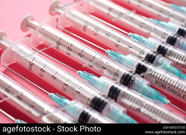 Close-up of a group of syringes on a pink table