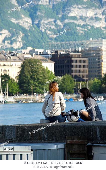 Two young women relax by Lake Geneva, Geneva, Switzerland, Europe