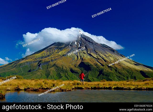 A man in front of Mount Taranaki in New Plymouth, New Zealand