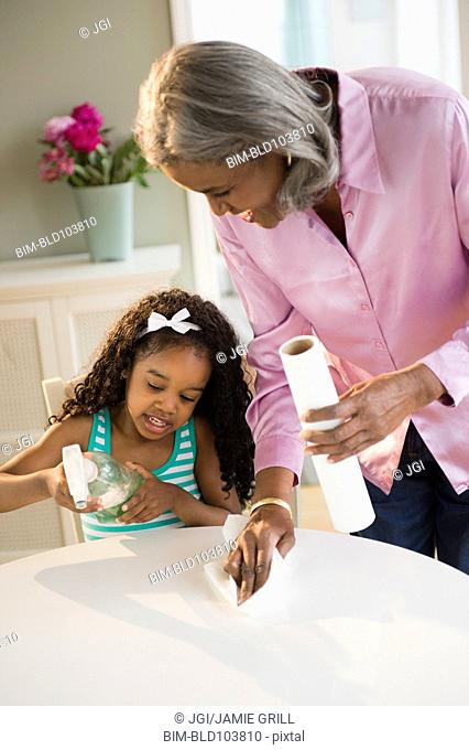African American grandmother and granddaughter cleaning the table