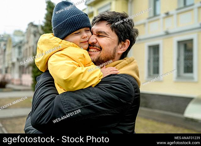 Happy father embracing son wearing knit hat