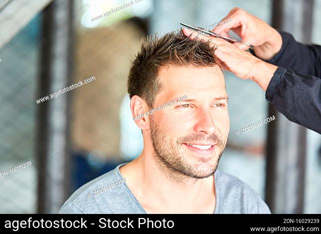 Mann bekommt einen Haarschnitt mit der Schere beim Friseur oder zu Hause