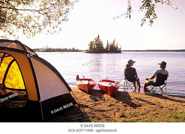 Couple relaxing at Otter Falls campground Whiteshell Provincial Park, Manitoba, Canada