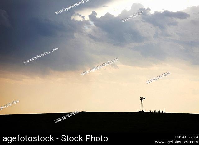 Crepuscular rays, also known as god beams, shine down toward a lone windmill after the passage of a powerful thunderstorm, Colorado