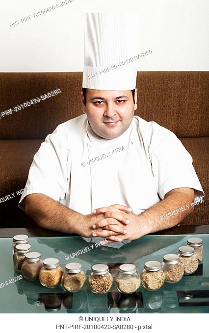 Chef smiling with assorted spices on a table, Gurgaon, Haryana, India
