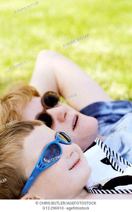 Woman and 3 years old boy wearing sunglasses looking toward the sky. Boise, Idaho. USA