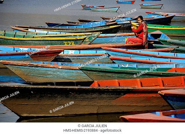 Nepal, Pokhara, woman in red among the colourful wooden boats on th lake Phewa Tal