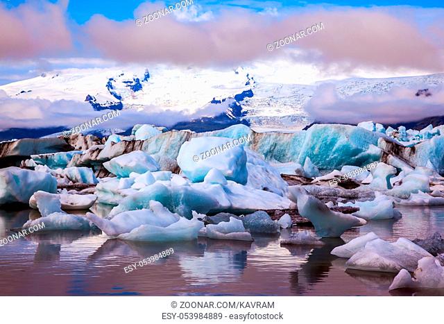 Icebergs and ice floes are reflected in the smooth water surface. Drift ice Ice Lagoon - Jokulsarlon, Iceland. The concept of extreme northern tourism