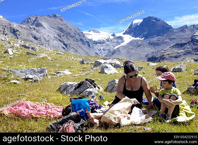 Family, packed lunch in the alpine meadows during a hike along the trails of the Stelvio National Park, Italy