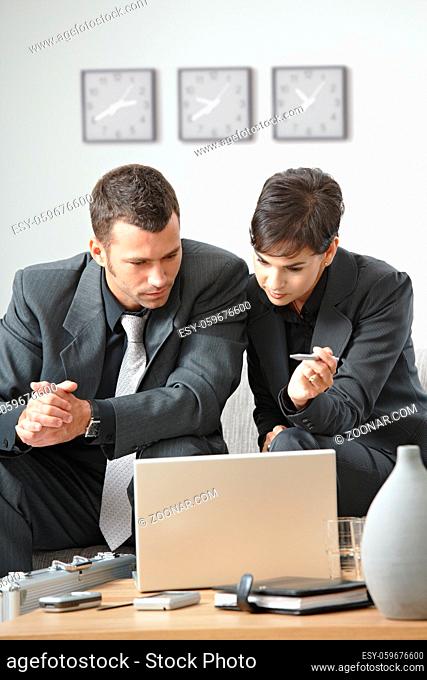 Young business people having meeting at office sitting on couch working on laptop computer