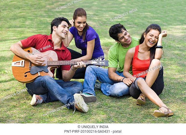 Man playing guitar with his friends sitting beside him