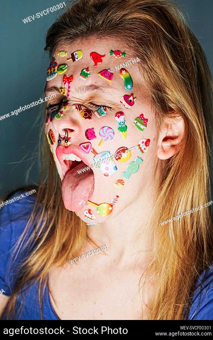 Woman with stickers over face sticking out tongue