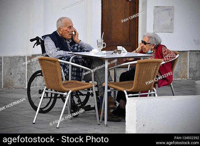 Little going on on Tamariz Beach in Estoril on 08/21/2020. Two local very old people, couple, pensioners, seniors are sitting at a table and drinking espresseo...
