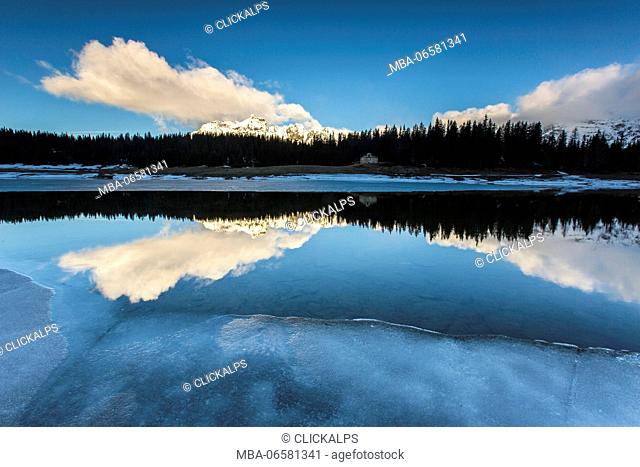 The spring thaw melts ice while snowy peaks are reflected in Lake Palù Sondrio Malenco Valley Valtellina Lombardy Italy Europe