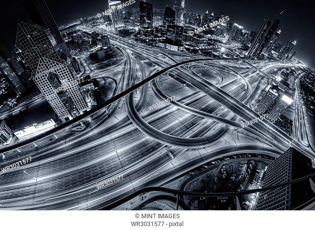 Aerial view of Dubai, United Arab Emirates at dusk, with illuminated highways in the foreground
