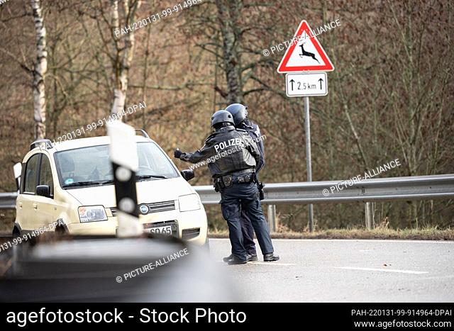 31 January 2022, Rhineland-Palatinate, Mayweilerhof: Police officers check a car at a barricade on county road 22, about a kilometer from the scene where two...