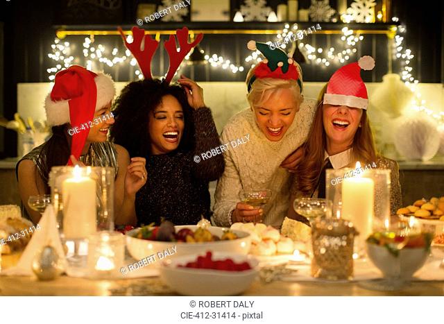 Laughing friends enjoying candlelight Christmas dinner