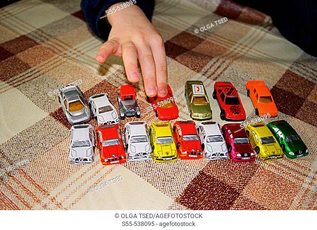 A little boy of 5 years playing with toy cars and cars of chocolate presented to him by his grandmother. While playing, sometimes eats one or two cars
