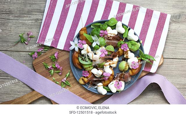 Summer salad with grilled peaches, ham, mozzarella hearts and basil