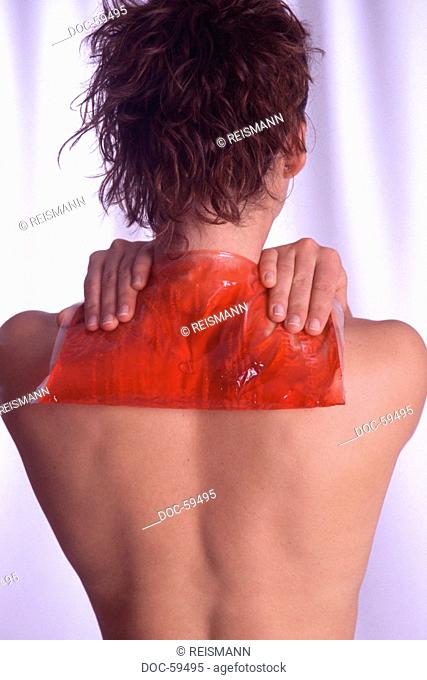 Young woman treating her shoulder with a warm gel compress