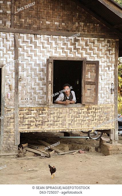 Myanmar  Man in the window of a ratan farm house,  Myitkyina, a largely Kachin community in north Burma near the Chinese border