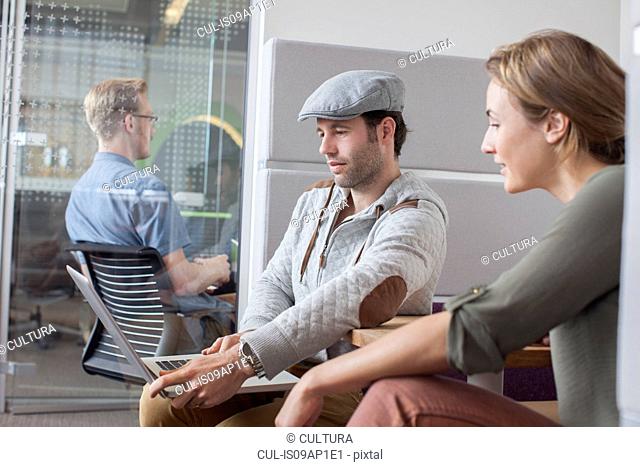 Man and woman looking at laptop in office meeting