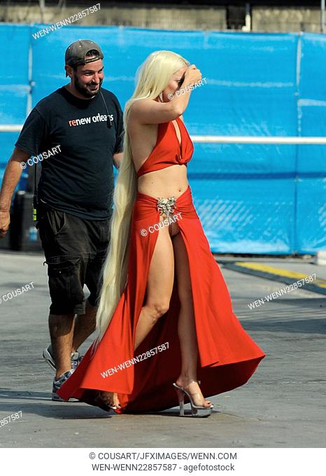 Lady Gaga leaves little to the imagination as she steps out of her trailer in a red dress with a long slit that showed off her toned legs for a scene in...