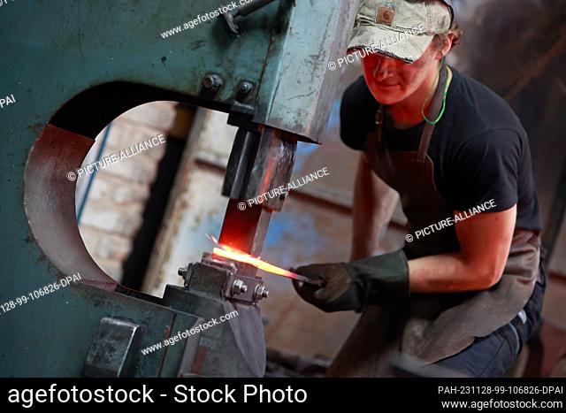 28 November 2023, Saxony-Anhalt, Wernigerode: Michele, an apprentice at the Harz smithy, makes a Celtic sword. The object is a copy of a more than 1000-year-old...