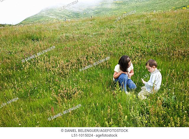 Boy and girl playing on a meadow in the mountains of Somiedo