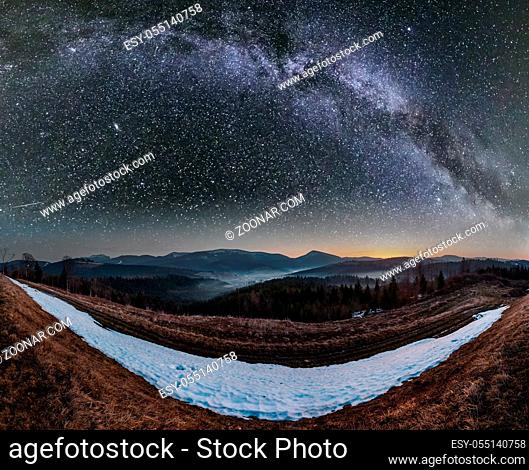 Spring starry night Carpathian mountains plateau landscape with snow-covered ridge tops in far and Milky Way in sky, Ukraine