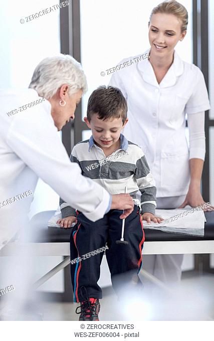 Doctor examining little boy with reflex hammer